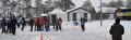 Schaatsers en publiek op de besneeuwde ijsbaan bij de kantine in Alteveer
